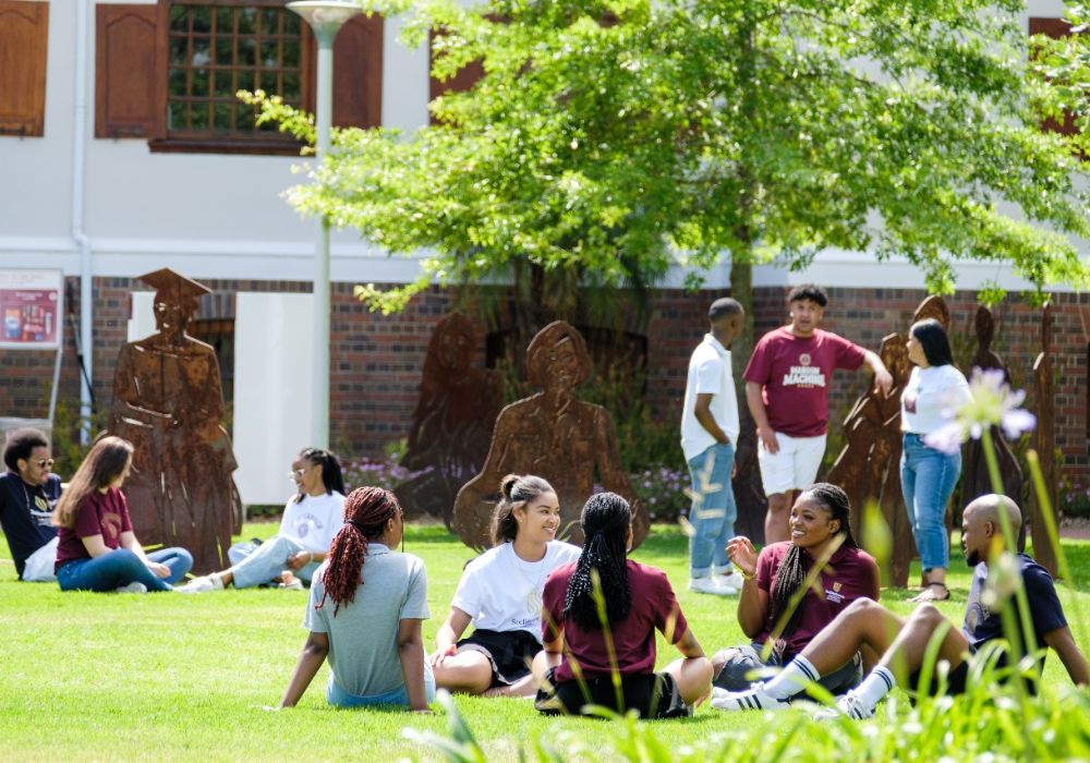 Students relaxing on the grass in front of a building at Stellenbosch University, South Africa.